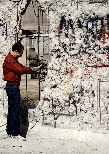 Ein Mann schlägt Mauerstücke aus der ehemaligen Grenzmauer, 1990
