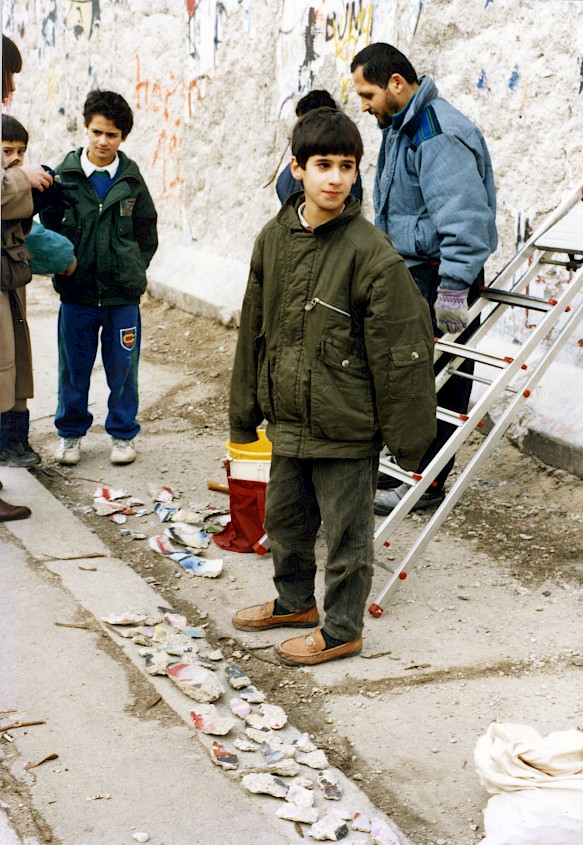 Kinder und Jugendliche aus Kreuzberg schlagen Stücke aus der Mauer heraus. Anschließend verkaufen sie die Mauer-Stücke als Andenken.