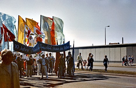 Der 1.Mai war ein wichtiger Feier-Tag in der DDR. Hier laufen Menschen mit Fahnen vor der neuen Mauer an der Mühlenstraße.